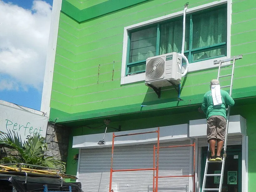 Instalador colocando una unidad de aire acondicionado en la fachada de un edificio
